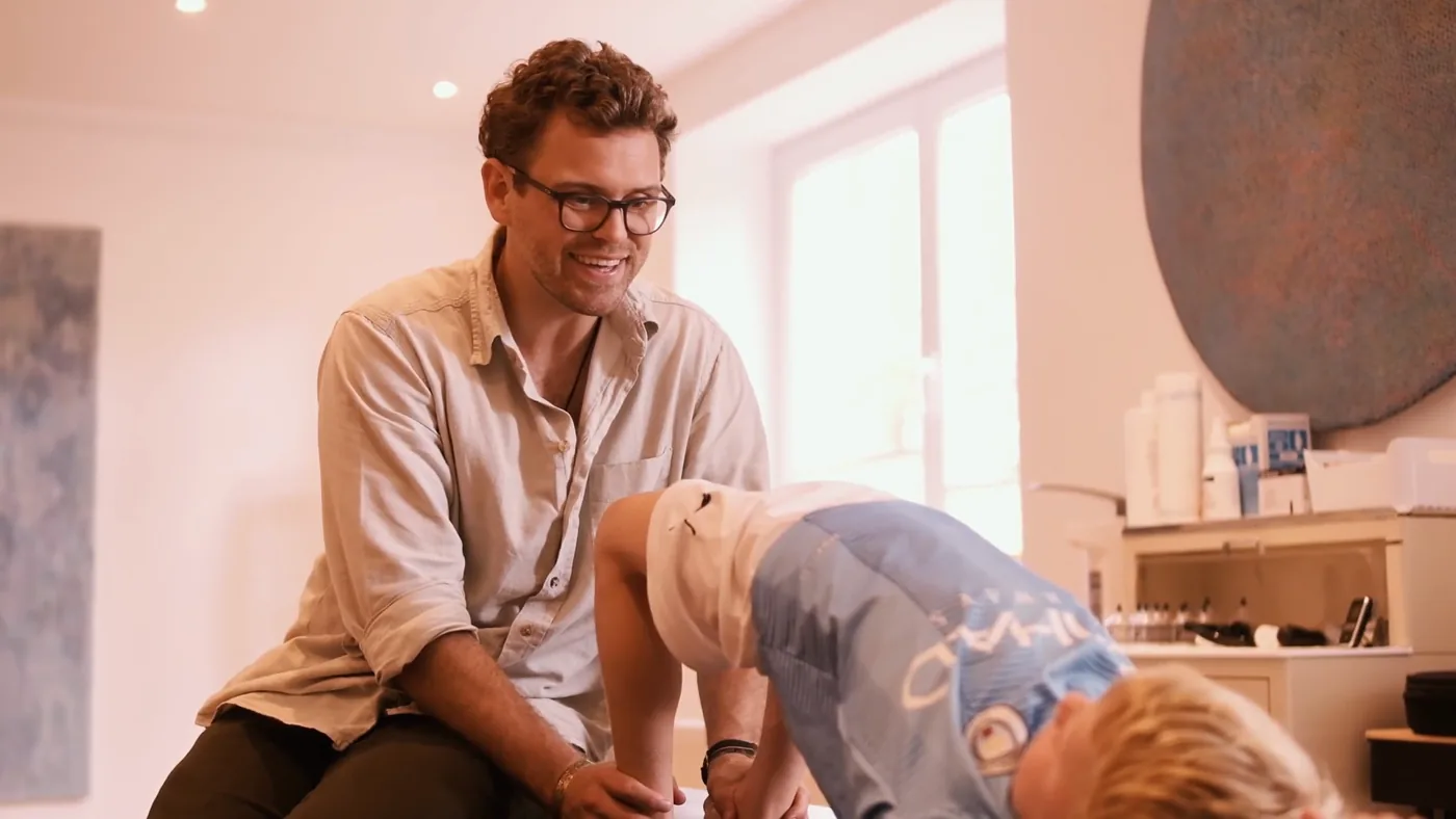 Trainingstherapie: Tim Raav begleitet einen Jungen bei einer Übung auf der Behandlungsliege