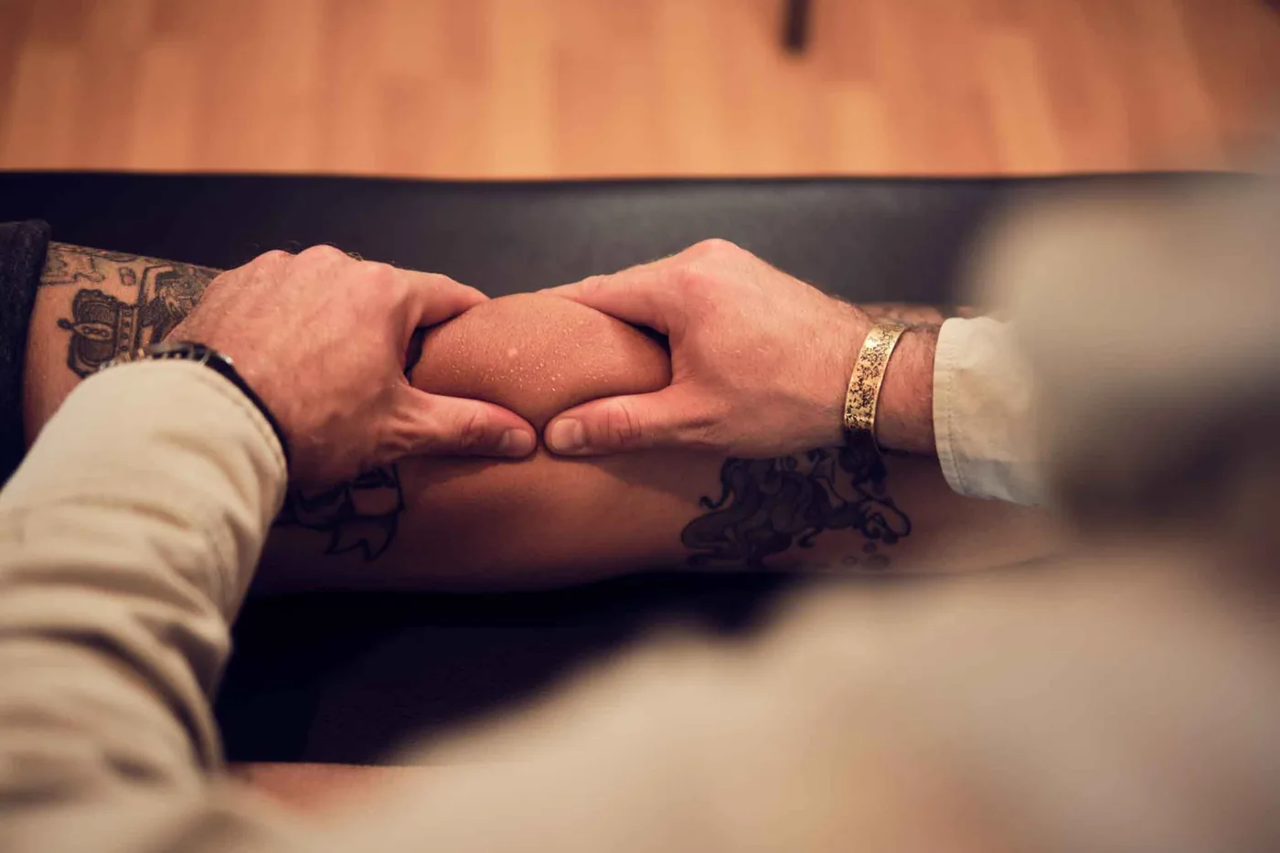 Weichteilbehandlung der Wade: Beide Hände greifen den Wadenmuskel eines liegenden Patienten